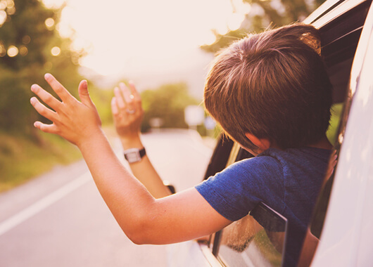 Kids hanging heads and hands out of a car window.