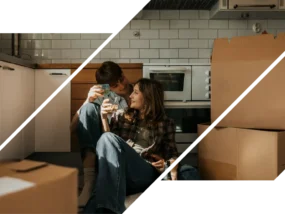 A man and woman sitting in a kitchen with moving boxes.