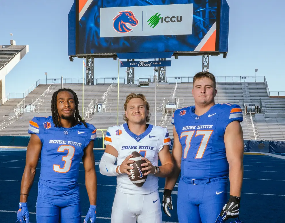 Boise State Football student-athletes Maddux Madsen, Latrell Caples, and Kage Casey in front of a Jumbotron showing the Broncos and ICCU logos.
