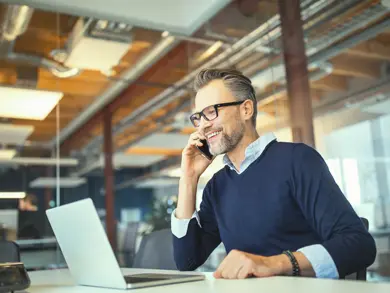 Man on talking on phone while browsing computer