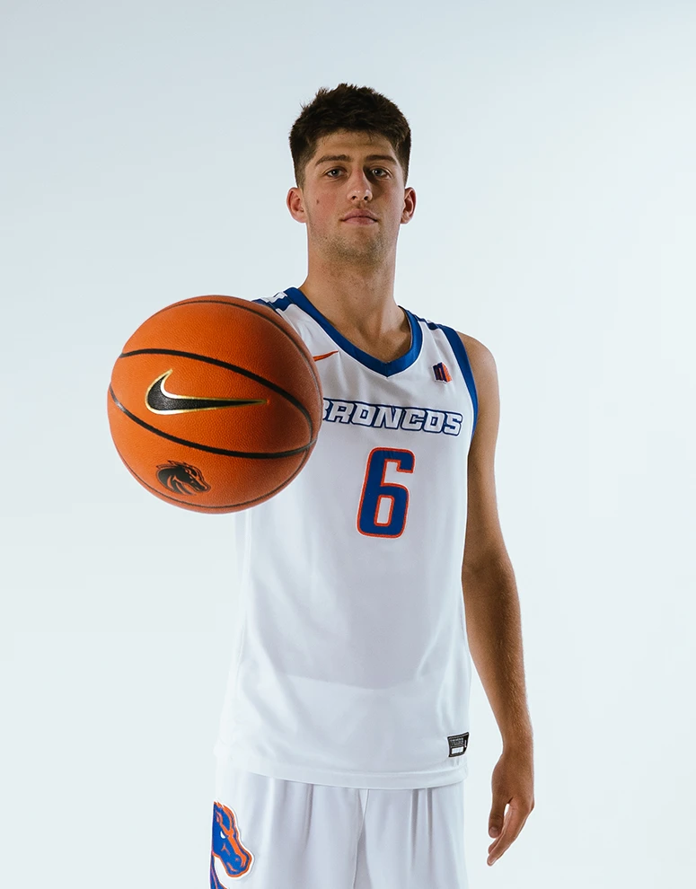 Pearson Carmichael poses confidently holding a basketball with the Boise State Broncos logo.