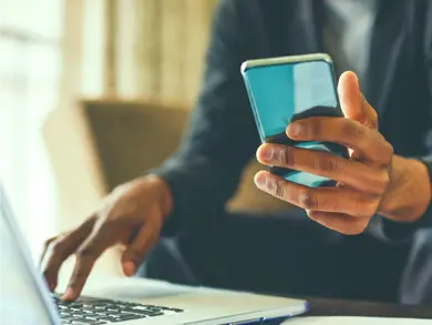 Man holding phone while browsing computer
